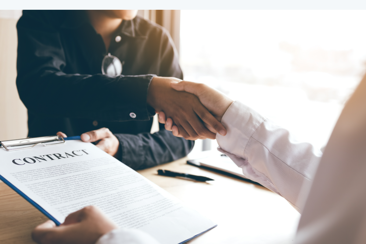 Dos personas estrechando la mano tras firmar un contrato laboral